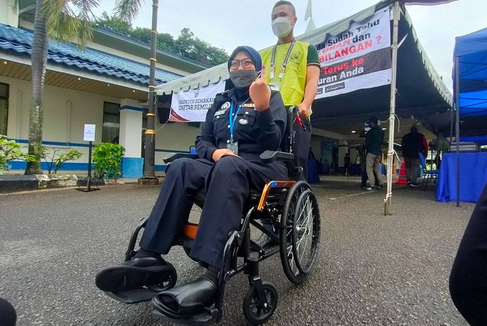 Siti Nor Maslinda menunjukkan jarinya selepas selesai membuang undi di Dewan Serbaguna Ibu Pejabat Polis Kontinjen (IPK) Melaka di Bukit Beruang di sini, pada Isnin.