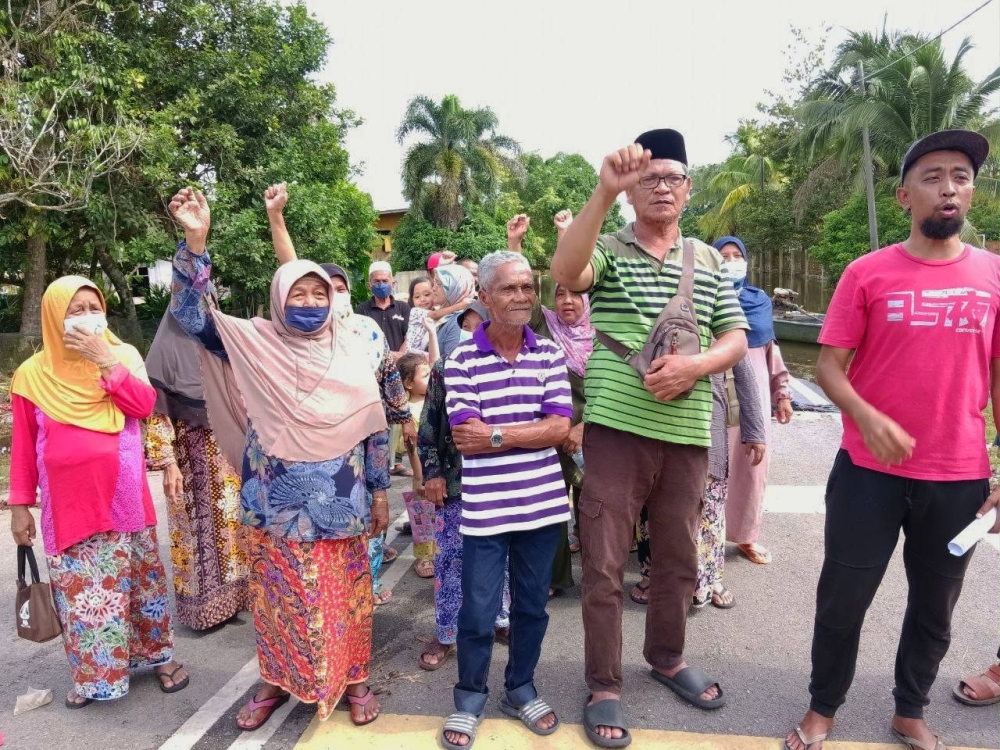 Sebahagian daripada mangsa banjir termenung mengadakan himpunan aman di depan PPS SK Tok Deh, Rantau Panjang pada Selasa.