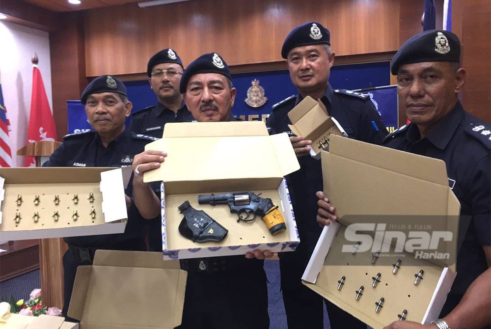 Muhamad Zaki (tengah) menunjukkan pistol yang dirampas dalam serbuan di sebuah rumah tumpangan di Kota Bharu. Foto SINAR HARIAN