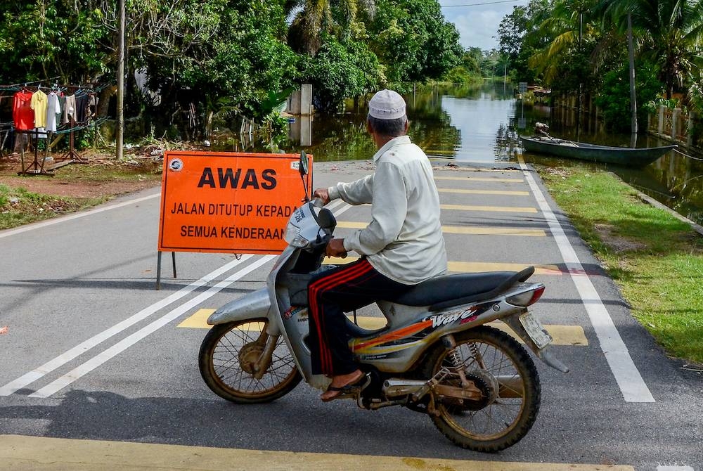 Seorang penduduk terpaksa berpatah balik apabila jalan Kampung Gual Tok Deh ke Kampung Tersang dinaiki air banjir ketika tinjauan hari ini. Foto Bernama