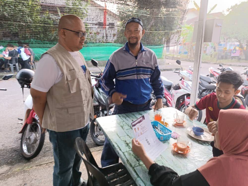 Khairul Anuar (kiri) beramah mesra dengan penduduk ketika kenduri rakyat di Tanjung Dawai di Sungai Petani pada Rabu.