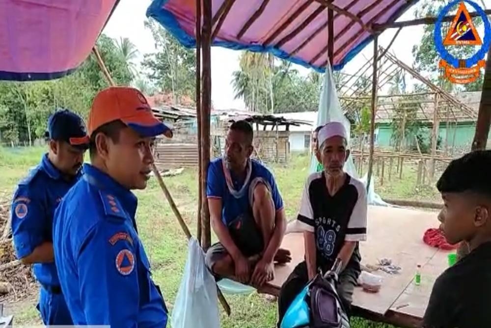 Mohd Arif (kiri) bertanyakan khabar kepada mangsa banjir yang terpaksa membina pondok sendiri di Kampung Putat Tujuh, Rantau Panjang.