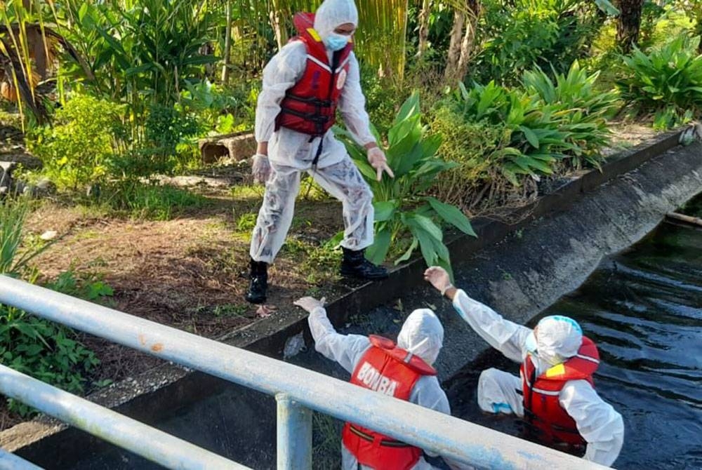 Anggota bomba membantu menaikkan mayat mangsa ditemui lemas di dalam palung di Parit 8 Gambut di sini pada Rabu.