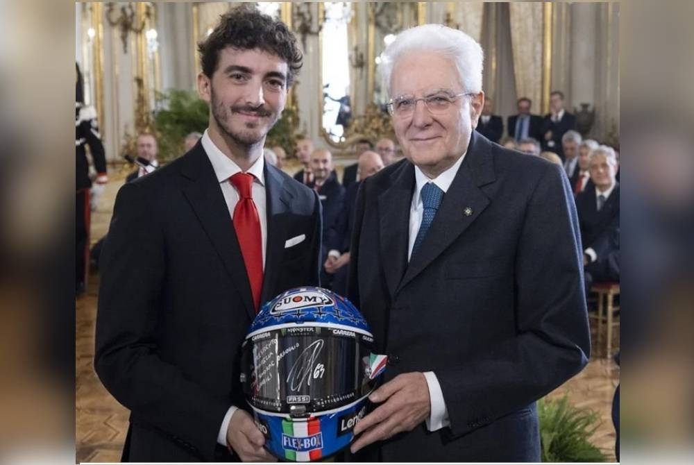 Bagnaia (kiri) menghadiahkan topi keledar kepada Mattarella di Rom pada Rabu. -Foto Agensi