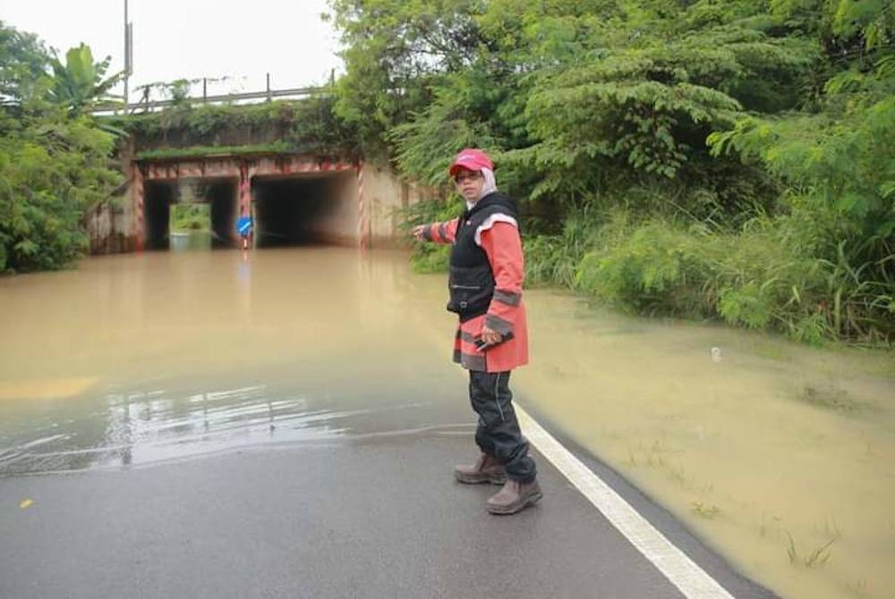 Aiman Athirah menunjukkan jalan yang ditenggelami air ketika membuat tinjauan di sekitar Kampung Sri Tanjung pada Khamis.