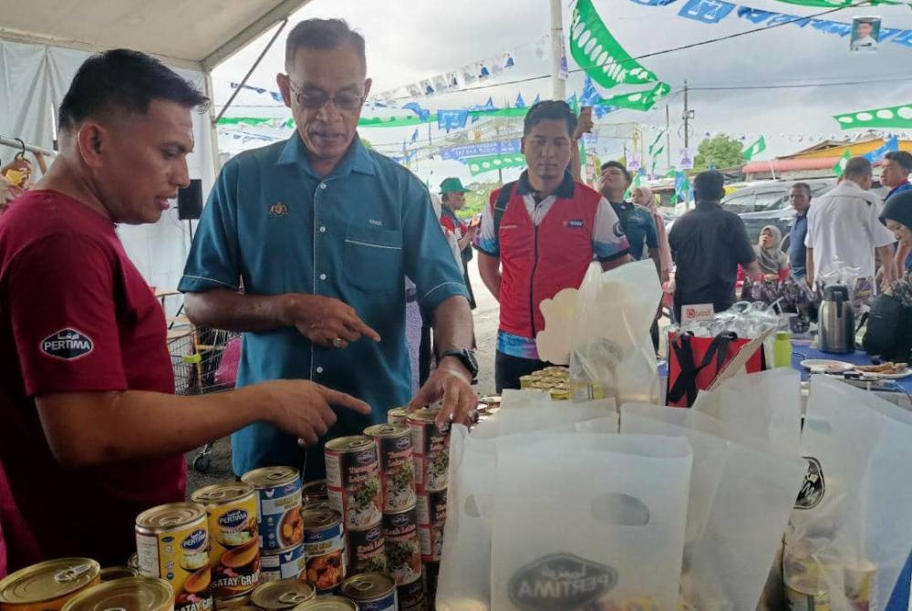 Rosol (dua dari kiri) berbual dengan peniaga ketika Program Jualan Keluarga Malaysia di Kampung Batu Hampar pada Khamis.