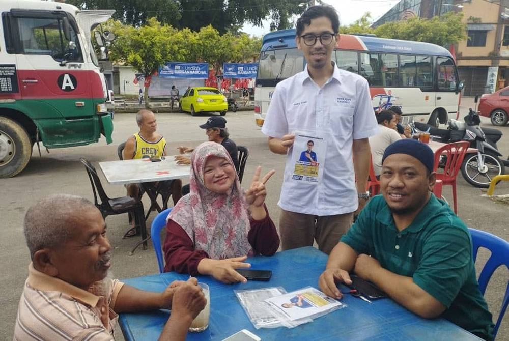 Mohd Fazrul (dua dari kanan) bertemu penduduk setempat dan mengedarkan risalah berkenaan empat tawarannya semasa berkempen di pekan Simpang Renggam, Kluang pada Khamis.