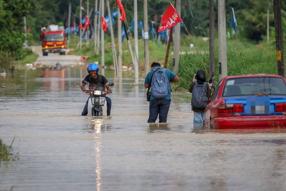 Penunggang motosikal meredah air yang memenuhi jalan akibat dari limpahan air Sungai Langat di Kampung Sri Tanjung pada Khamis. - Foto Bernama