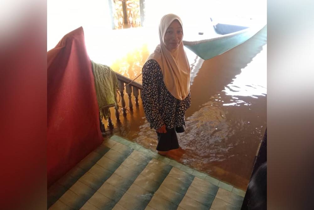 Norizan berada di ruang hadapan rumahnya yang masih ditenggelami banjir.