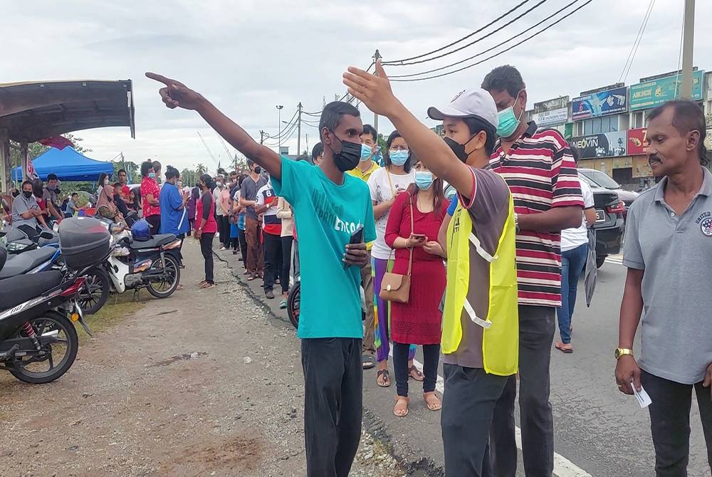 Muhammad Ikmal menunjukkan arah laluan kepada salah seorang pengundi di luar kawasan pembuangan undi pada Sabtu.