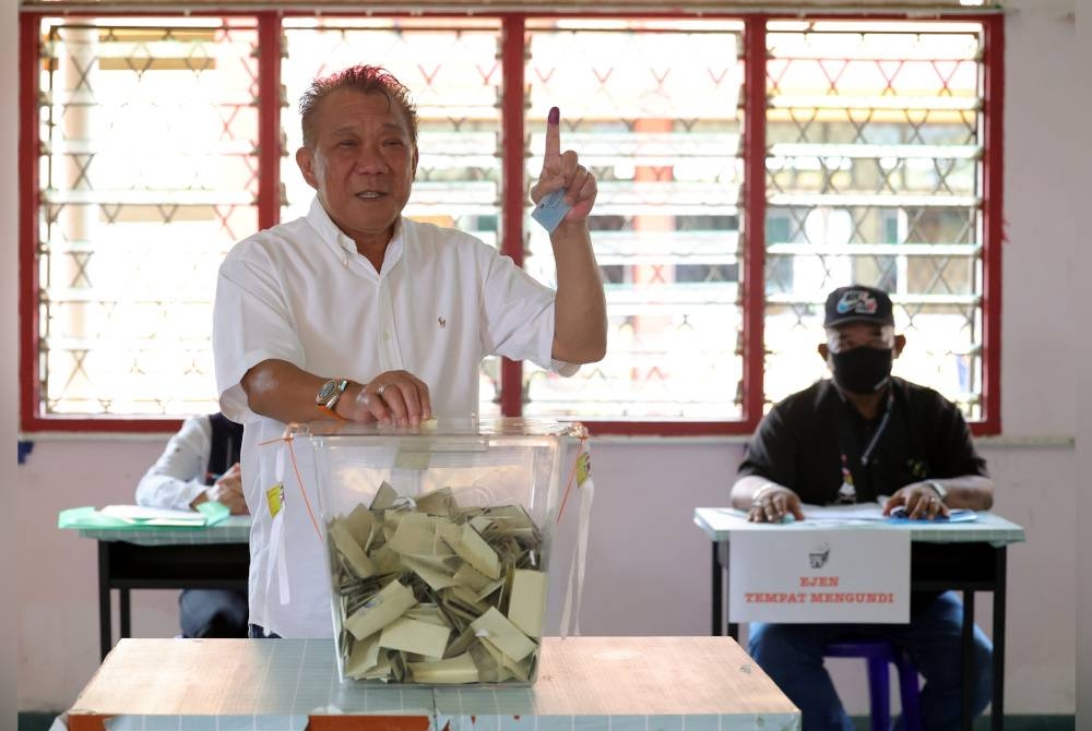 Calon BN Parlimen Kinabatangan Datuk Seri Bung Moktar Radin memasukkan kertas undi ke dalam peti ketika mengundi pada Pilihan Raya Umum ke-15 di Sekolah Menengah Kebangsaan Bukit Garam hari ini.- Foto Bernama