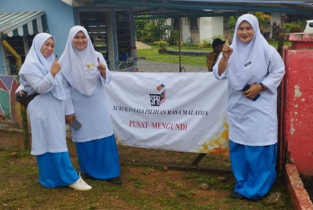 Tiga sahabat memilih memakai pakaian seragam sekolah untuk mengundi pada PRU15 di pusat mengundi Sekolah Kebangsaan Palong 3 di sini.