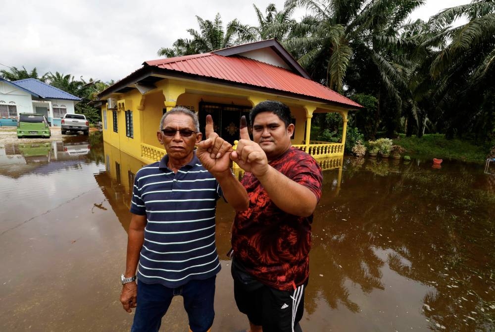 Mangsa banjir, Selamat Osman, 56, (kiri) bersama anak saudaranya Muhammad Fathi Mat Nayan, 29, menunjukkan celupan dakwat selepas mengundi sempena PRU15 di Pusat Mengundi SK Pasangan, Kampung Kuantan bagi Parlimen P096 Kuala Selangor hari ini. - Foto Bernama