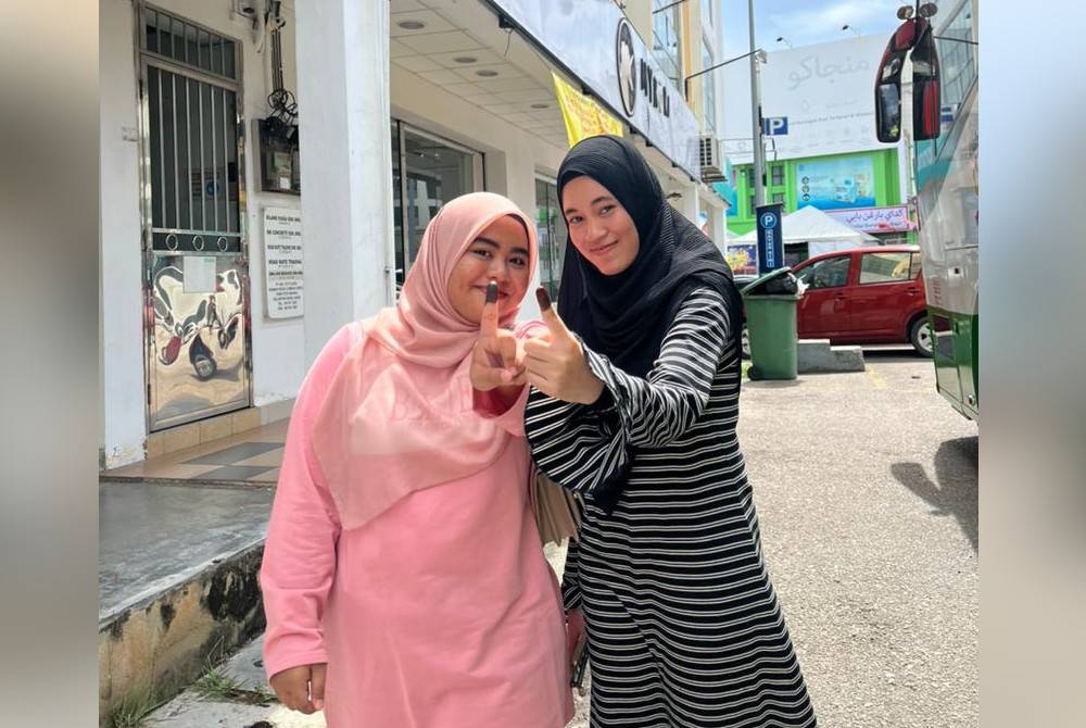 Siti Wahidah (kiri) bersama rakannya, Nur Farhanah Nasir selepa mengundi di SK Geting pada Sabtu.