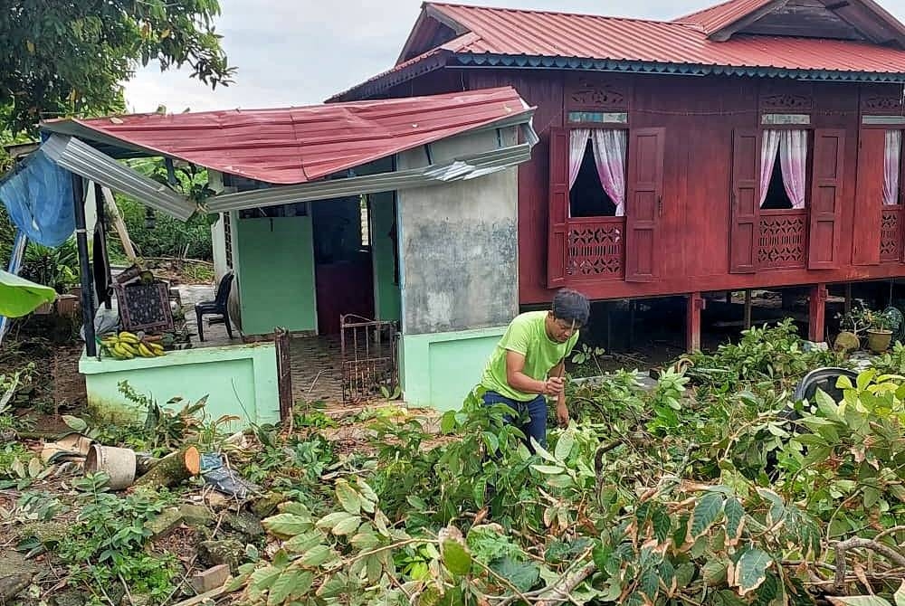 Mohd Radzi membersihkan kawasan rumahnya setelah dapur rumah dihempap pokok rambutan dalam kejadian ribut di Kampung Serkam Darat, di sini pada Rabu.