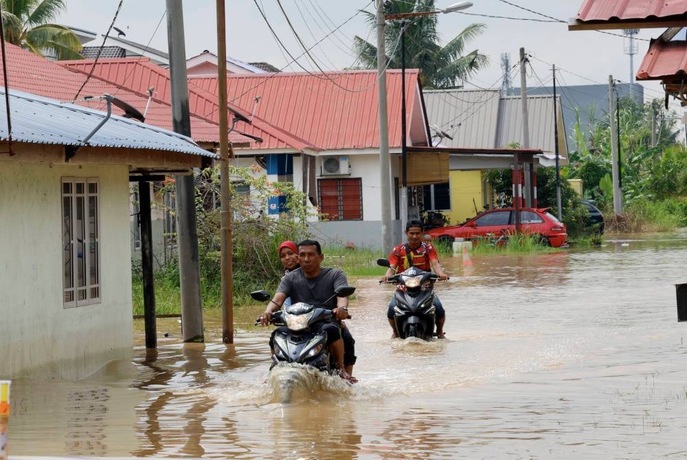 Penduduk sekitar Meru terpaksa menggunakan motosikal meredah banjir selepas kawasan rumah mereka dinaiki air banjir. - Foto Bernama