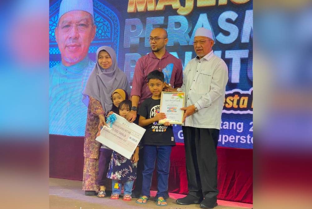 Ahmad (kanan) menyampaikan anugerah keluarga bestari kepada pemenang pada Majlis Perasmian Penutup Hari Iqra dan Pesta Buku Darul Naim 2022 di Tunjong, Kota Bharu pada Sabtu.