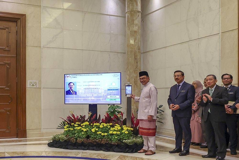 Perdana Menteri, Datuk Seri Anwar Ibrahim mengimbas kad perakam waktu pada mesin elektronik pada hari pertama beliau memulakan tugas di pejabatnya di Perdana Putra. - Foto Bernama