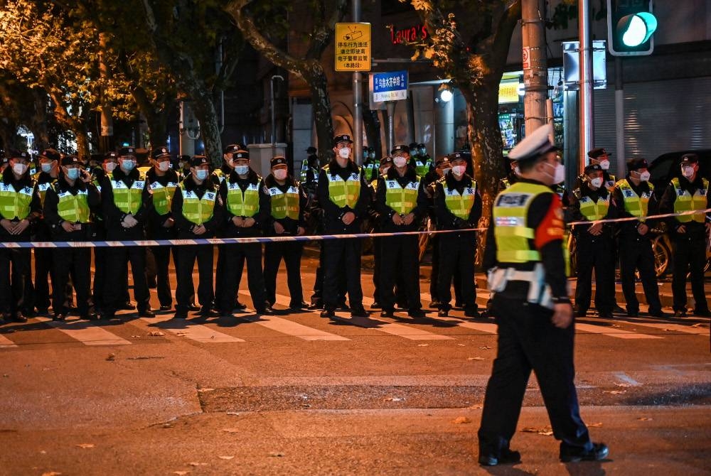 Anggota polis menyekat jalan di Shanghai bagi untuk menghalang protes orang ramai membanjiri jalan Wulumuqi. - AFP