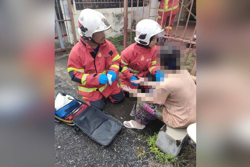 Anggota bomba memberikan rawatan awal terhadap salah seorang mangsa kebakaran sebuah rumah teres di Taman Sunway, Batu Caves di sini pada Selasa.