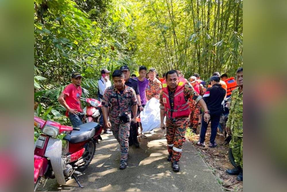 Mohd Adnin (kanan) bersama anggota membawa jenazah keluar dari lokasi kejadian di air terjun Lata Goleng, Kampung Sungai Rual, Jeli pada Selasa.