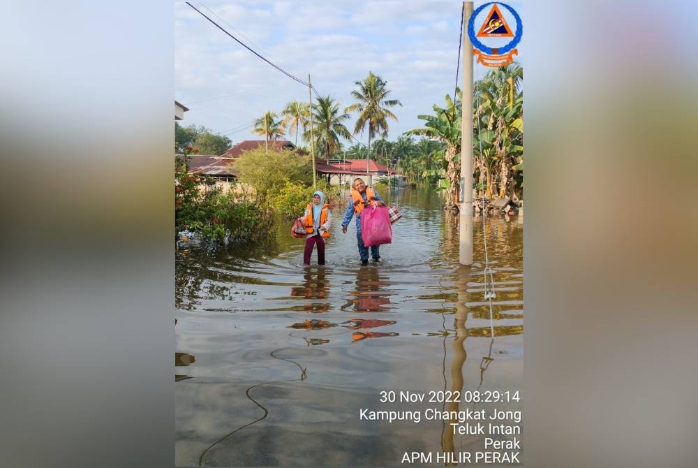 Anggota APM membantu penduduk kampung berpindah ke lokasi lebih selamat akibat banjir di Batu 9, Simpang Tiga pada Rabu. - Foto ihsan APM