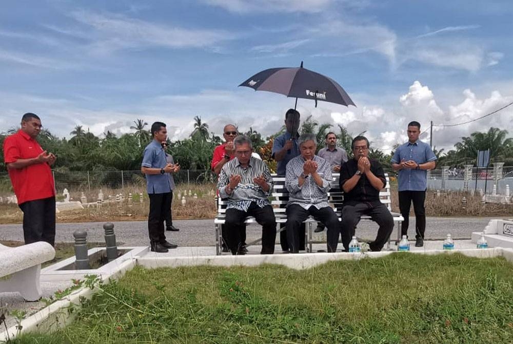 Ahmad Zahid (duduk, tengah) menziarahi kubur ibu bapanya di Tanah Perkuburan Islam Tebuk Chek Maja, Sungai Nipah Darat, Bagan Datuk pada Ahad.