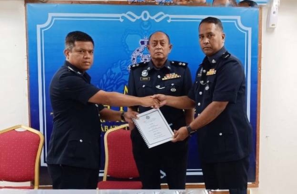 Pemangku Timbalan Ketua Polis Daerah Kemaman, Asistan Superintendan Mohd Khairi Abdullah (kiri) menyerahkan dokumen serah terima tugas Timbalan Ketua Polis Daerah kepada Deputi Superintendan Wan Muhamad Wan Ja’afar (kanan) sambil diperhatikan Ketua Polis Daerah Kemaman, Hanyan Ramlan (tengah) di Rumah Kelab Ibu Pejabat Polis Daerah (IPD) Kemaman di Kemaman pada Ahad