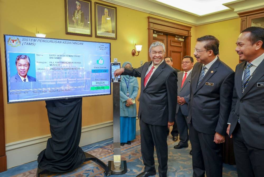 Ahmad Zahid mengimbas kad perakam waktu pada sistem pengurusan kedatangan bagi memulakan tugasnya sebagai Timbalan Perdana Menteri di Bangunan Perdana Putra pada Isnin. - Foto Bernama