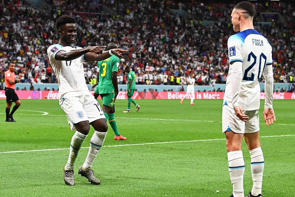 Saka (kiri) meraikan kejayaan selepas melebarkan kedudukan England ketika berdepan Senegal di pusingan 16 terbaik Piala Dunia Qatar 2022 di Stadium Al Bayt, Al Khor. FOTO: EPA