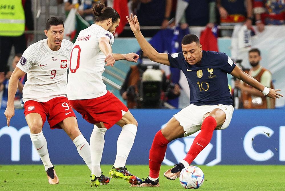 Mbappe (kanan) cuba melepasi pertahanan Poland dalam aksi di Stadium Al Thumama pada awal pagi Isnin. - Foto EPA