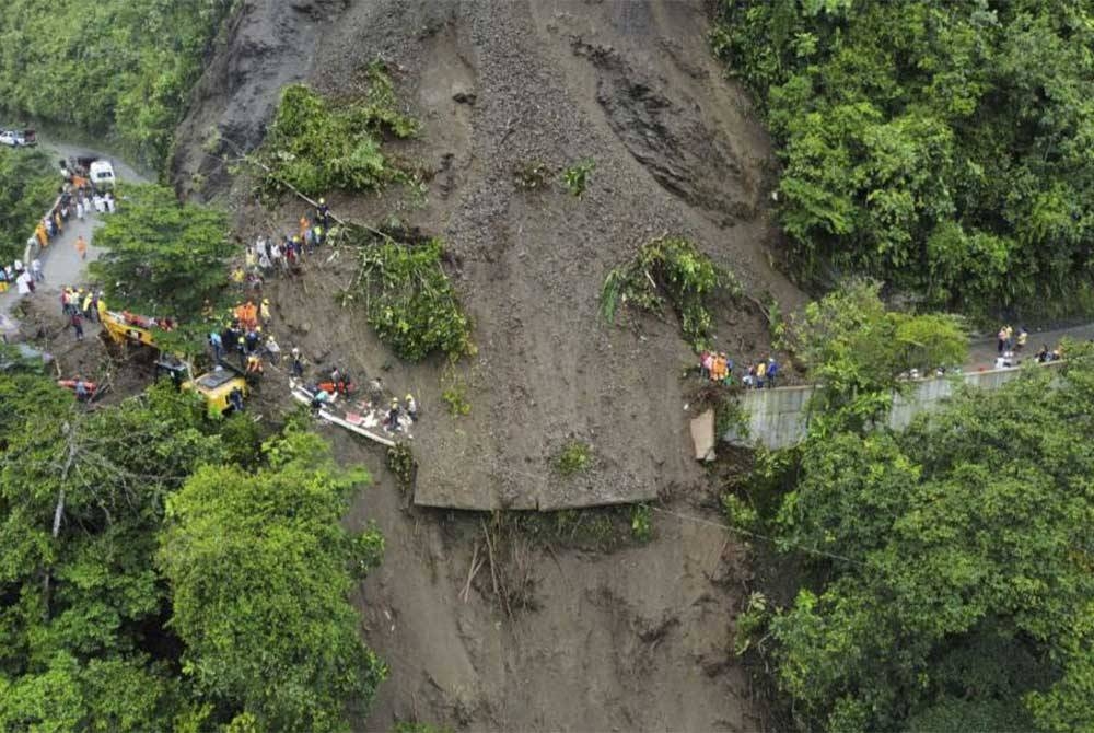 Kejadian tanah runtuh telah menimbus sebuah bas yang membawa penumpang serta sebuah kereta dan motosikal. Foto AFP.