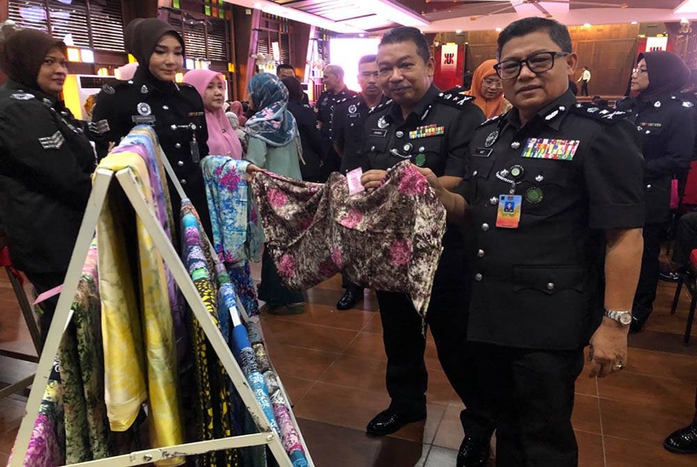 Mat (kanan) melihat produk penjara iaitu batik yang dijual di Program Outreach Memperkasa Komuniti Koreksional We Care Peringkat Penjara Kelantan pada Rabu.