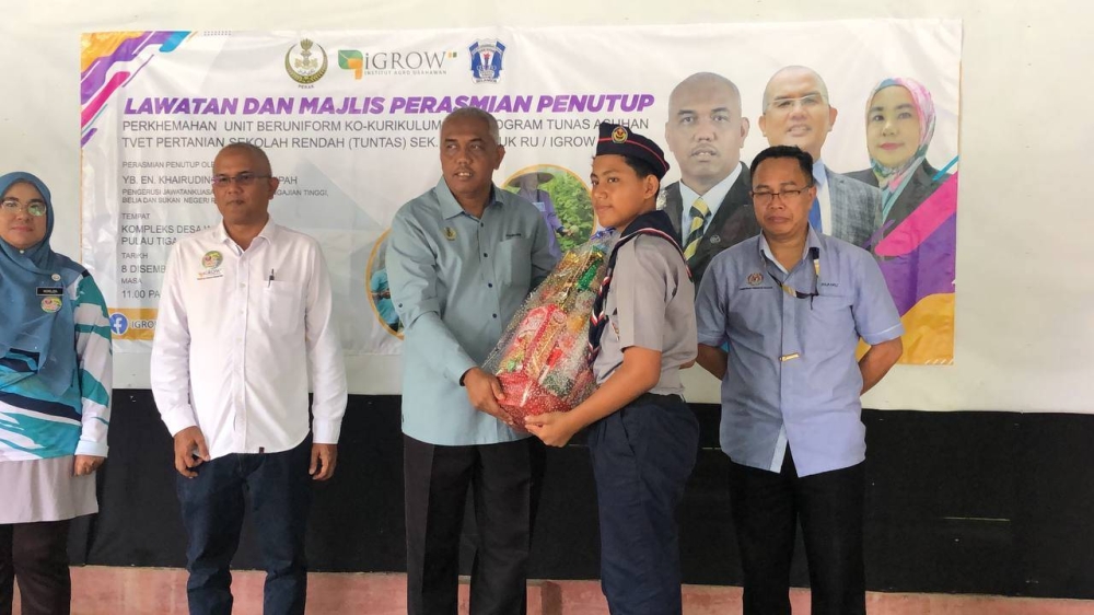 Khairudin (tengah) menyampaikan hadiah kepada peserta yang menyertai perkhemahan unit beruniform kokurikulum dan program Tunas Asuhan TVET Pertanian Sekolah Rendah (Tuntas) di Kompleks Desa Warisan IGROW, Kampung Gajah.