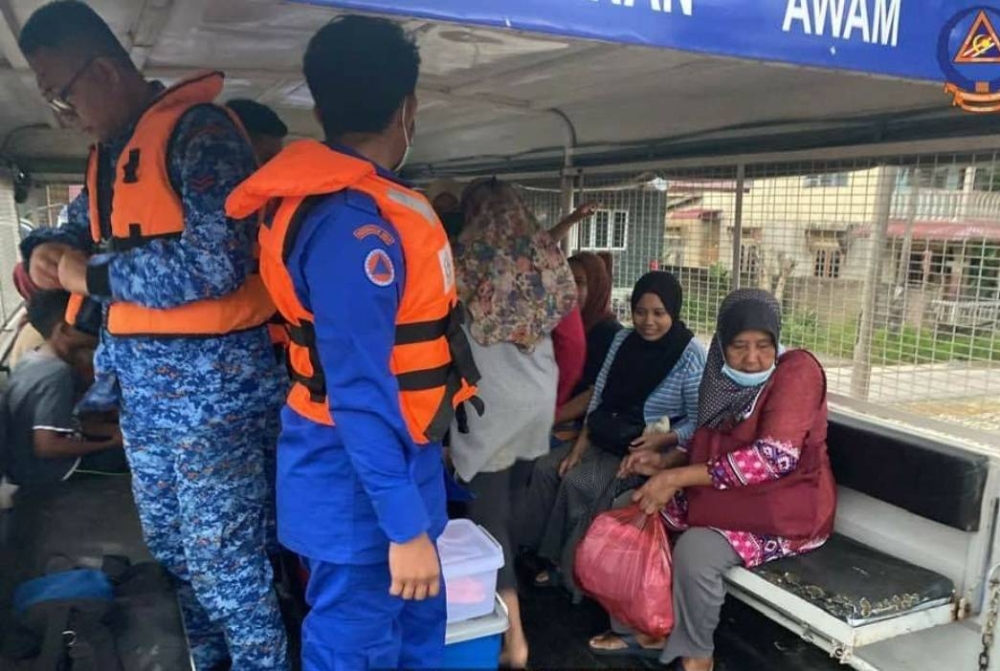 Anggota APM membantu memindahkan mangsa banjir di daerah Temerloh ke PPS yang dibuka selepas beberapa kawasan dilanda banjir kilat. Foto FB APM PAHANG