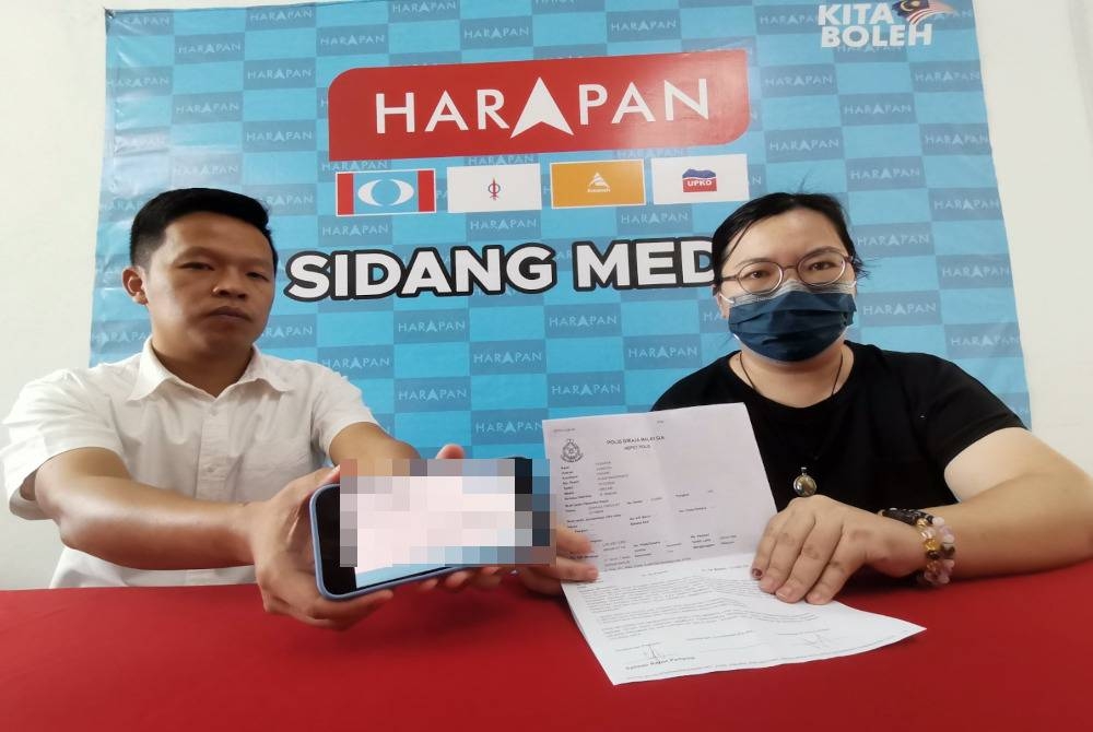 Lee (kanan) menunjukkan laporan polis yang dibuat pada Khamis lalu dalam satu sidang media bersama Chun Kuan di Pusat Khidmat Komuniti DUN Semambu pada Jumaat.