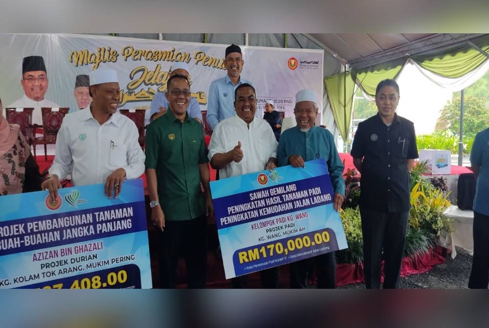 Muhammad Sanusi (tiga dari kanan) semasa menyerahkan replika cek bagi Program Sawah Gemilang Peningkatan Hasil Tanaman Padi dan Peningkatan Kemudahan Jalan Ladang untuk Kampung Wang, Mukim Ah pada Majlis Penutup Jelajah Kedah Sejahtera Daerah Kubang Pasu.