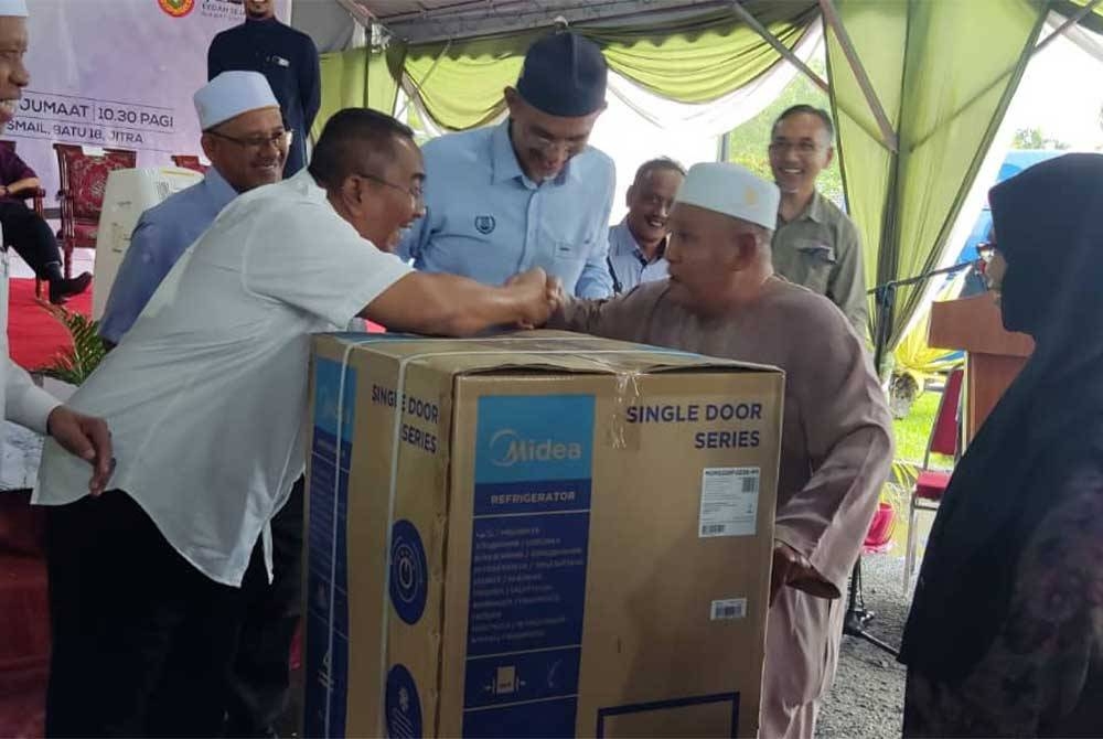 Muhammad Sanusi menyampaikan hadiah utama cabutan bertuah kepada seorang pengunjung di Majlis Penutup Jelajah Kedah Sejahtera Daerah Kubang Pasu di Masjid Haji Ismail, Batu 18, Jitra pada Jumaat.