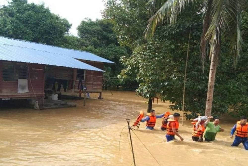 Anggota Angkatan Pertahanan Awam (APM) membantu memindahkan mangsa banjir dari Kampung Ulu Atok ke PPS di SK Ulu Atok, Raub pada Ahad. - Foto APM Pahang