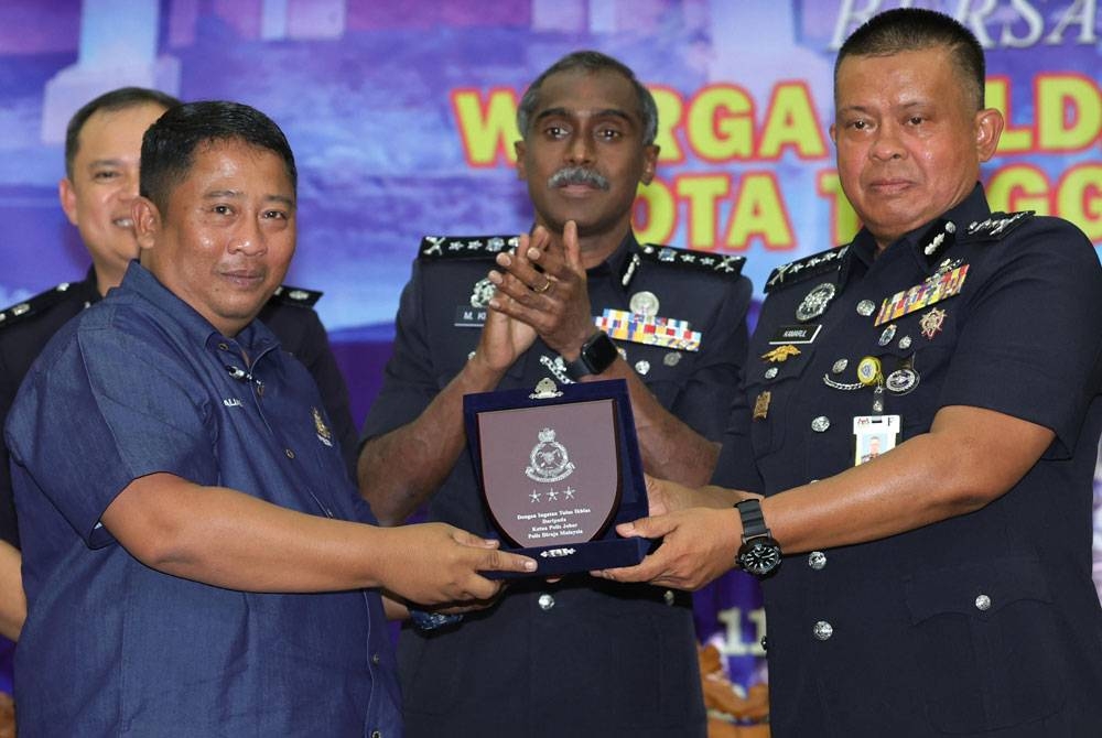 Kamarul Zaman menyampaikan plak cenderahati kepada Pengurus Felda Adela, Alias Mohamad pada Program Dialog Ketua Polis Johor bersama Warga Felda Daerah Kota Tinggi di Dewan Semai Bakti , Felda Gugusan Adela, Kota Tinggi, pada Ahad. - Foto Bernama