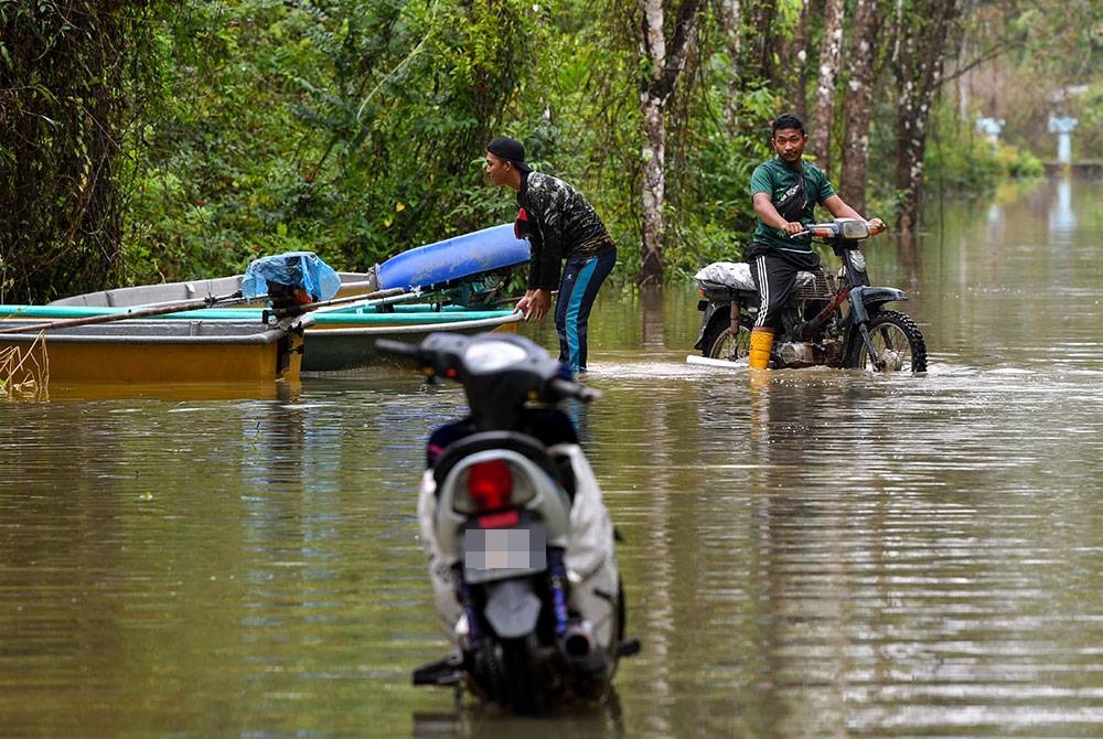 Penduduk kampung terpaksa menggunakan bot dan meredah banjir untuk melakukan kegiatan harian mereka. -Foto Bernama