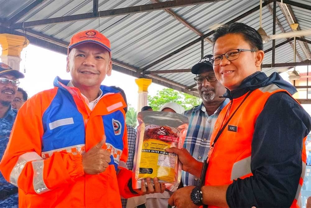 Muhammad Razmee (dua dari kanan) menunjukkan pek makanan awal mangsa banjir yang menggunakan teknologi retort di Pahang kepada Armizan (kiri) ketika melawat PPS SMK Seri Semantan pada Selasa