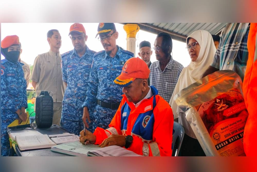 Armizan (duduk) menandatangani buku pelawat ketika lawatannya ke PPS SMK Seri Semantan pada Selasa.