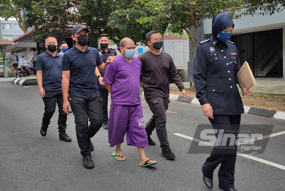 Tertuduh berbaju ungu diiring polis sebaik tiba di mahkamah.