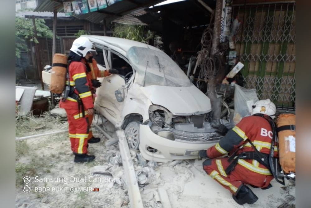 Anggota bomba memeriksa keadaan kereta Perodua Viva. - Foto Polis Tangkak