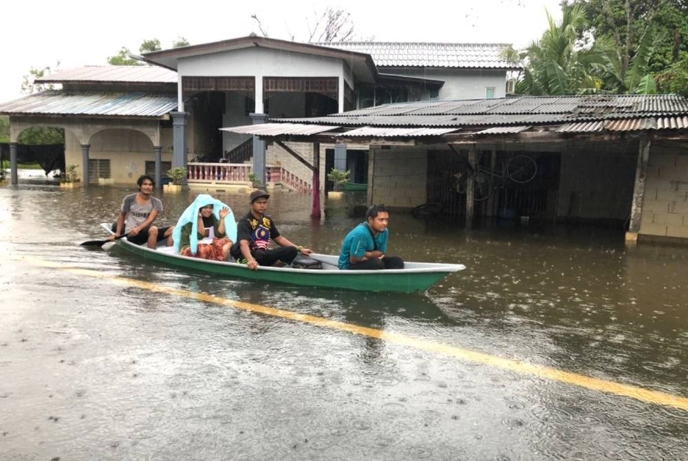 Mangsa banjir di Kampung Kusar, Rantau Panjang, Kelantan menaiki bot untuk berpindah ke pusat pemindahan sementara (PPS) berhampiran pada Ahad.