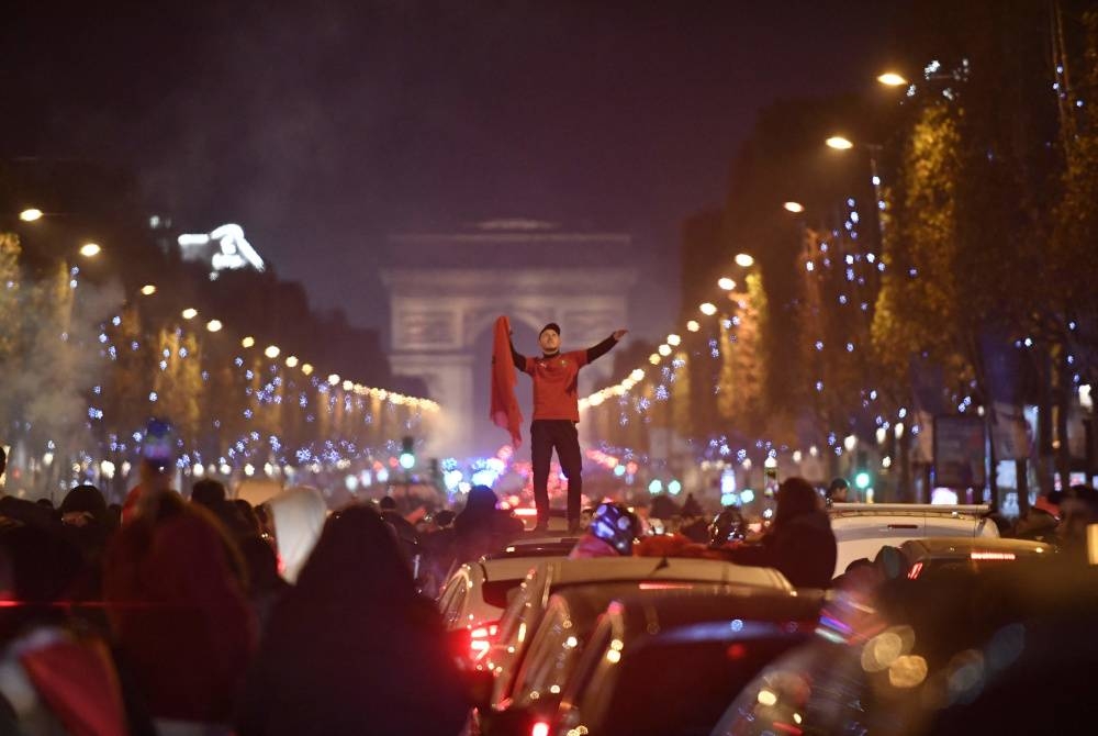 Seorang penyokong The Atlas Lions meraikan kemenangan Maghribi ke atas Sepanyol selepas perlawanan Piala Dunia Qatar 2022 di Champs-Elysees di Paris pada 6 Disember lalu. - Foto AFP