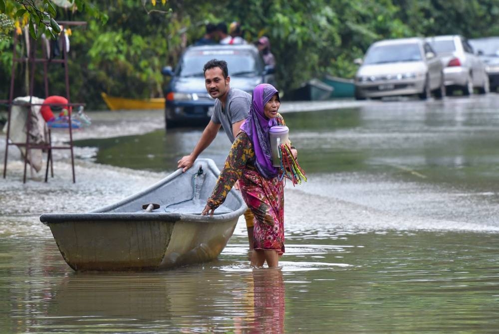 Penduduk menggunakan perkhidmatan sampan untuk melakukan kegiatan harian berikutan kawasan kampung masih ditenggelami banjir di Kampung Tersang, Rantau Panjang pada Rabu. - Foto Bernama