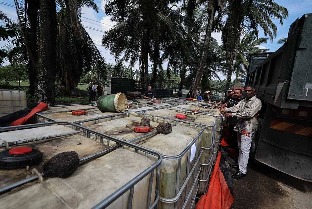 Jegan (kanan) bersama pegawainya menunjukkan 18 tangki plastik berkapasiti 1,000 liter minyak diesel bersubsidi yang dirampas dalam satu operasi di Valdor, Simpang Ampat, pada Khamis. - Foto Bernama