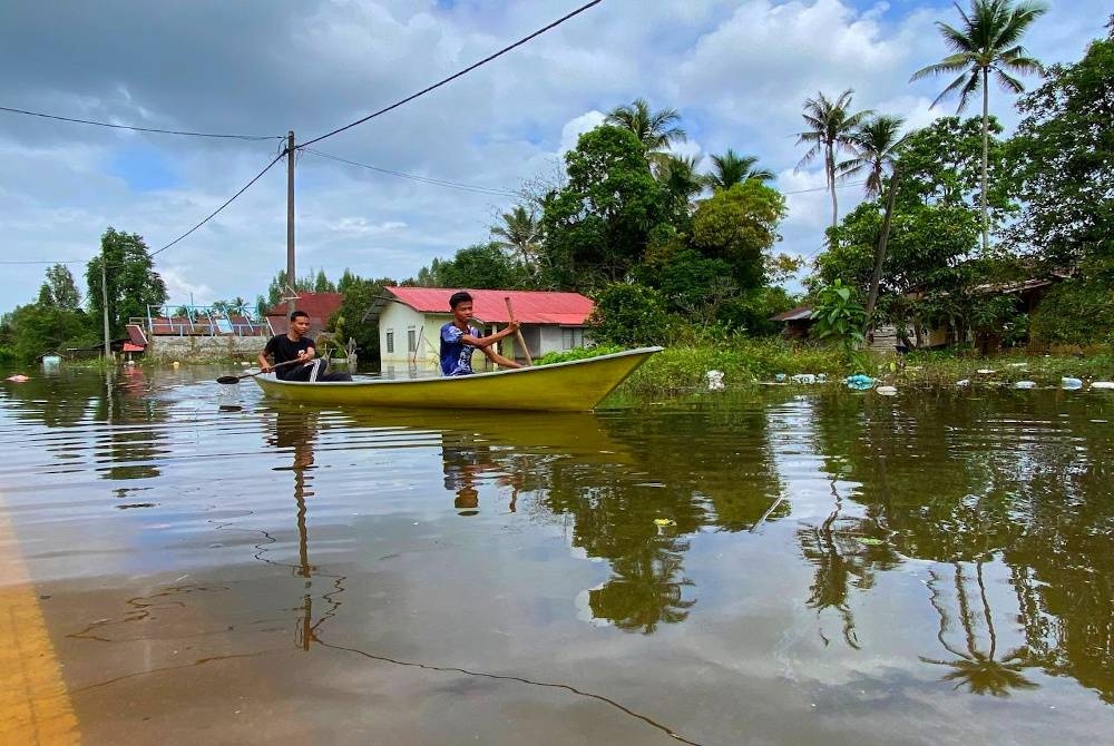 Penduduk terpaksa menggunakan perahu apabila Jalan Pengkalan Rakit-Batu Karang di Padang Licin, Rantau Panjang masih ditenggelami banjir.